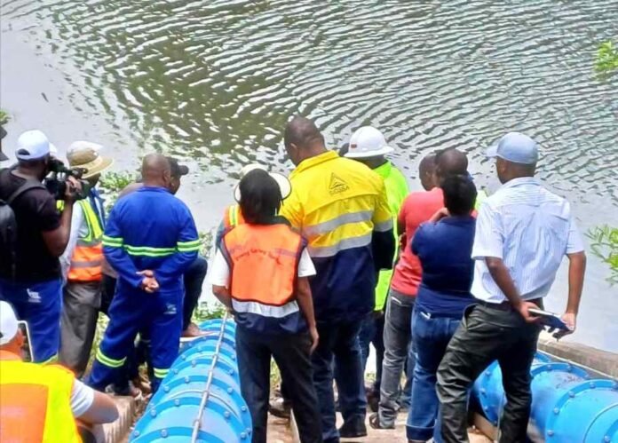 Officials in high-visibility gear inspect the Bronkhorstspruit Water Treatment Works beside large blue pipes.