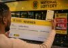 Unclaimed lottery money: What happens to winnings after 365 days Man holds R120 million National Lottery cheque and PowerBall ticket outside a lottery shop