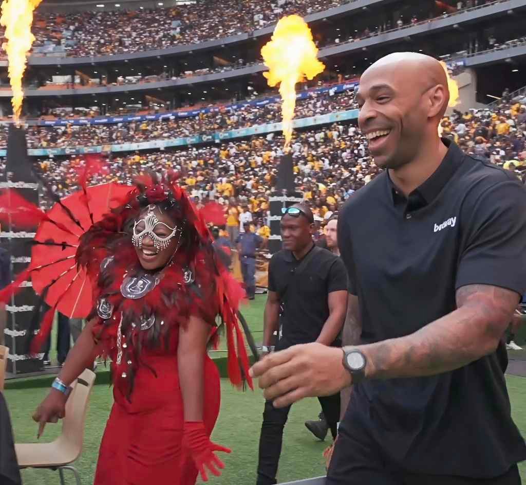 Thierry Henry smiling during a grand entrance with fireworks and a performer at the Soweto Derby.