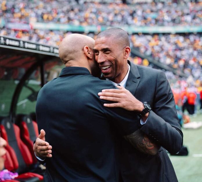 Thierry Henry smiling and hugging Orlando Pirates coach Abdeslam Ouaddou before the Soweto Derby.