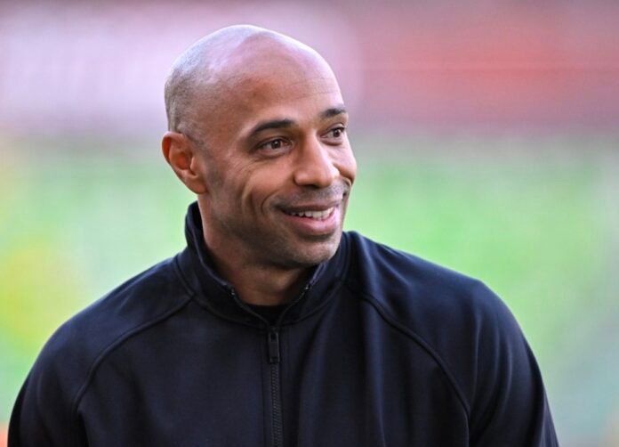Football legend Thierry Henry smiling in a black track jacket ahead of the Soweto Derby.
