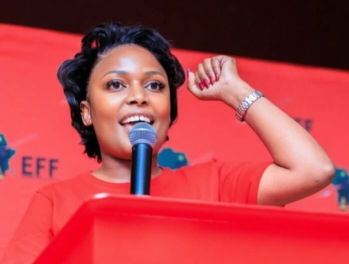 Tshegofatso Mashabela, Tshwane MMC for Health, speaks at a red podium with her right fist raised.